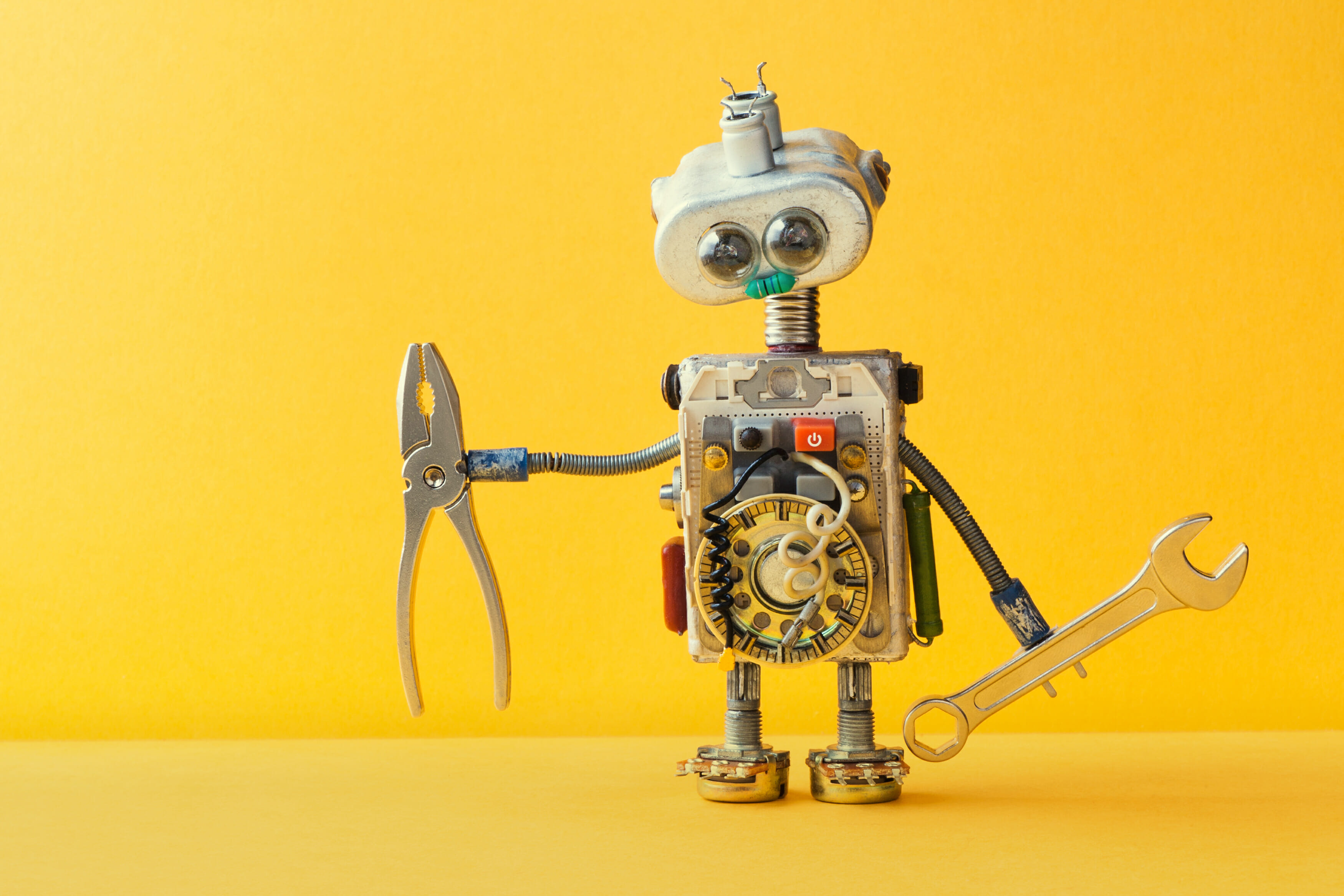 Hand wrench pliers robot handyman on yellow background. Cyborg toy lamp bulb eyes head, electric wires, capacitors vintage resistors