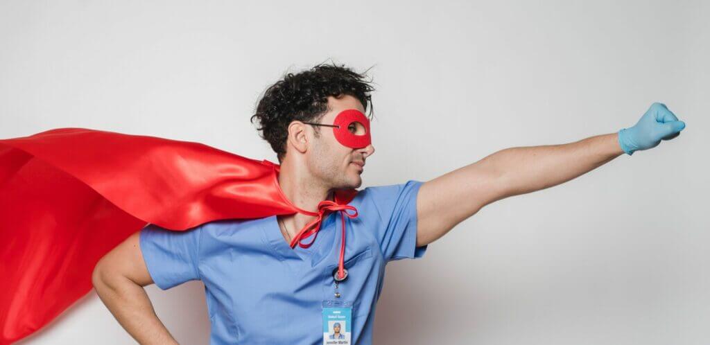 Ein Krankenpfleger trägt ein Superhelden-Kostüm und posiert wie Superman fürs Krankengeld.