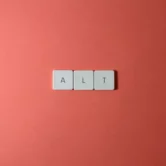 Drei Scrabble-Plättchen, die das Wort ALT formen