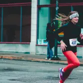 Frau in roter Hose und schwarzem Langarm-Top läuft einen Marathon.